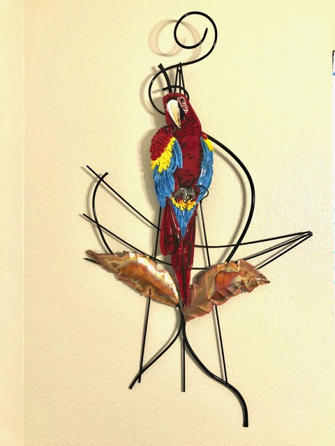 Red Parrot: a red fused-glass parrot perched, on a black wrought-iron armature with copper leaves below.