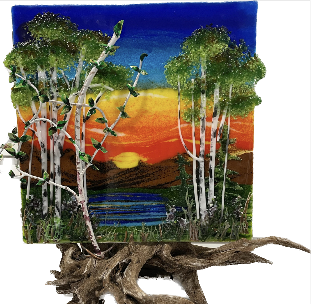 Fused-glass panel of birch trees against a warm sunset sky.