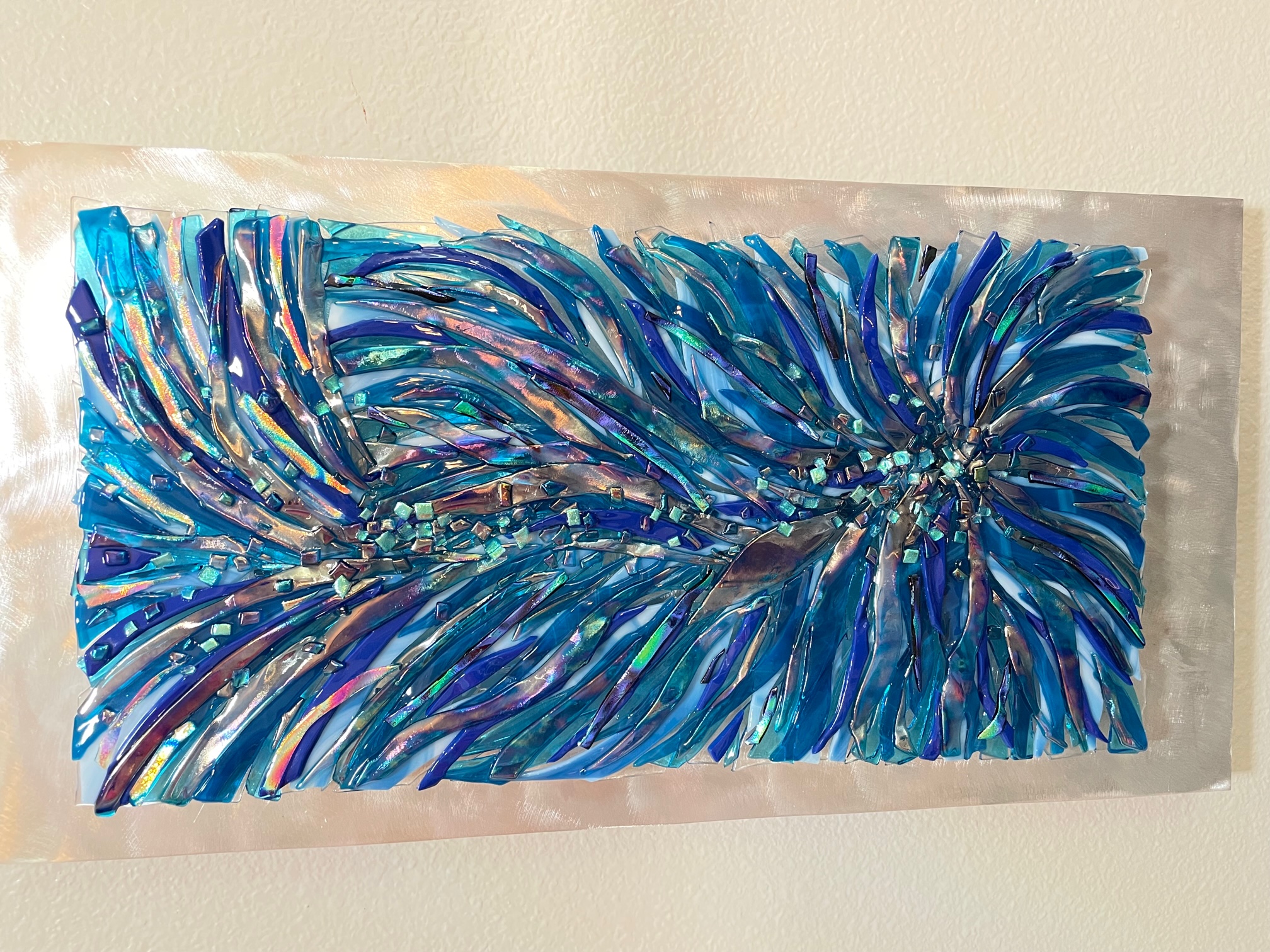 Fused-glass abstract feather in shades of blue.