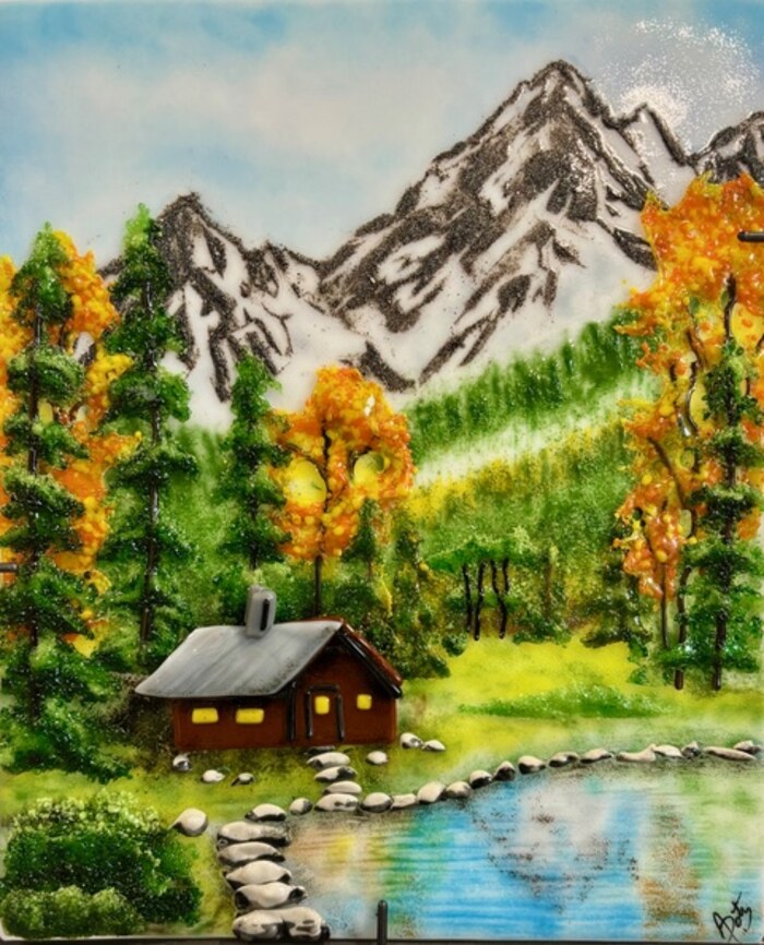 Fused glass mountain scene with snow-capped peaks, autumn aspens, a cabin, and a lake, by Annie Dotzauer