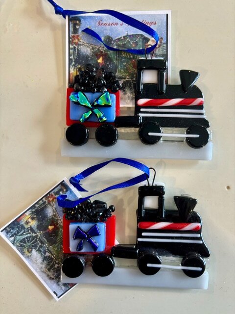Christmas Train: black fused-glass locomotive ornaments with a candy-stripe boiler and a coal car carrying a wrapped gift.