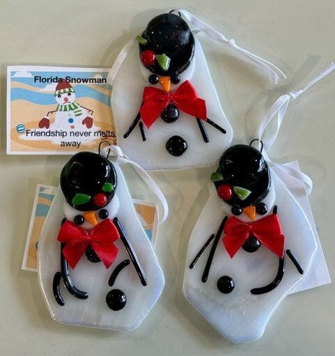 Florida Snowman: melting fused-glass snowman ornaments with a black top hat and red bow tie. The tag reads: friendship never melts away.
